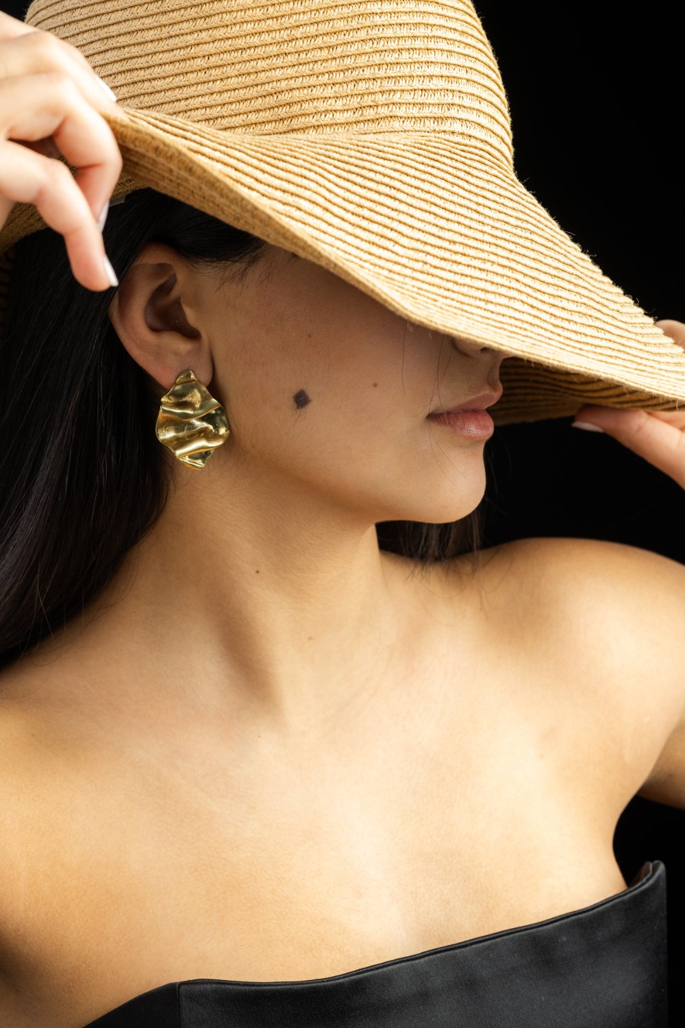 Model in a straw hat wearing gold earrings